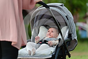 mother pushing happy infant baby stroller and walking in park