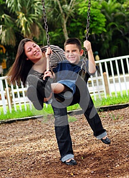 Mother pushing son on swing