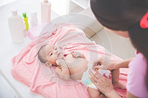 Mother put on a baby diaper to her newborn