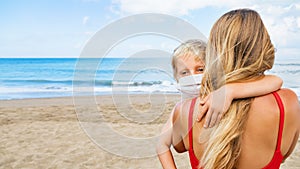 Mother put face mask on child on sea beach