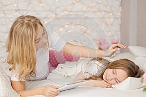 Mother put her daughter to sleep with tablet. Interior. Concept care