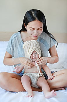 Mother put on some knit clothes to her baby on the bed