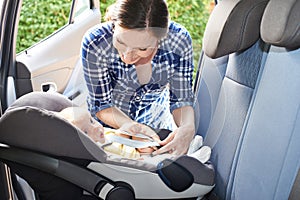 Mother Putting Baby Into Car Seat For Journey