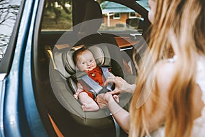 Mother putting baby in safety car seat family lifestyle