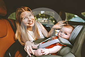 Mother putting baby in safety car seat happy family