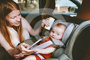 Mother putting baby in safety car seat mom and child together family