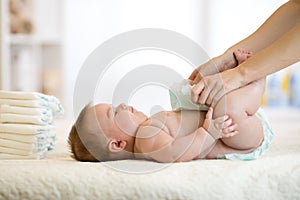 Mother putting diaper on her baby in nursery