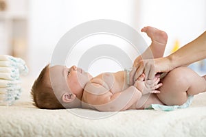 Mother putting diaper on her baby in nursery