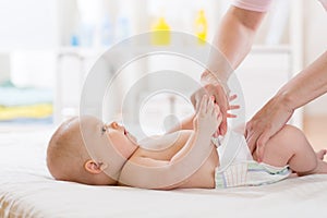 Mother putting diaper on her happy baby