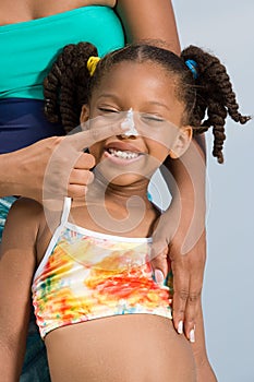 Mother putting suncream on daughters nose