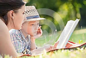 Mother read a tales for her son in summer garden