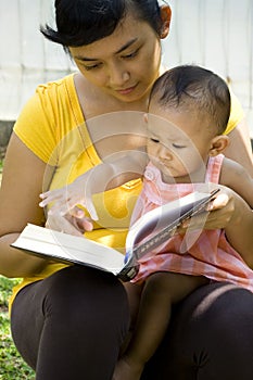 Mother reading while babysitting baby