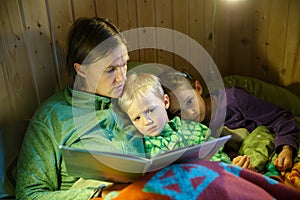 Mother reading bedtime stories to her kids before going to sleep