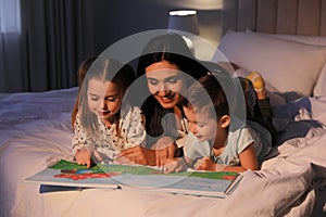 Mother reading bedtime story to her children at home