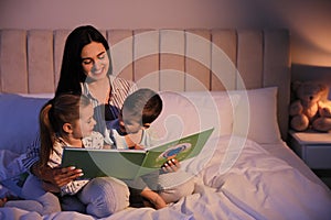 Mother reading bedtime story to her children at home