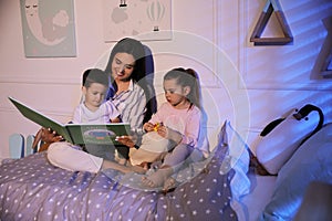 Mother reading bedtime story to her children at home