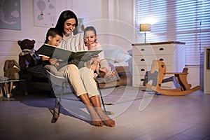 Mother reading bedtime story to her children at home