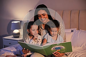 Mother reading bedtime story to her children at home