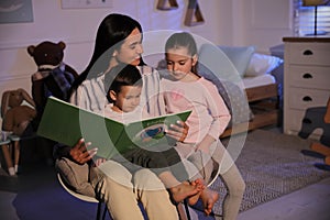 Mother reading bedtime story to her children at home