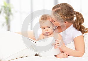 Mother reading book baby in bed before going to sleep