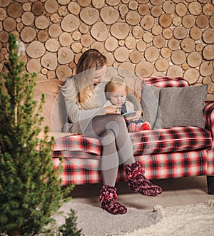 Mother reading a book with baby daughter before Christmas