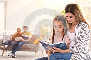 Mother reading book with child at home