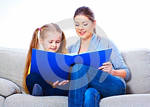 Mother reading book with daughter at home.