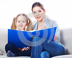 Mother reading book with daughter at home.