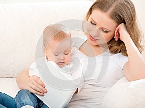 Mother reading a book a little baby on the sofa