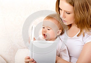 Mother reading a book a little baby on the sofa