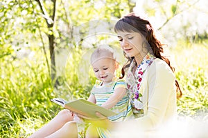 Mother reading book to baby outdoors