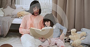 Mother Reading a Book to Daughter in the Child's Room