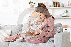 Mother reading book to her cute little toddler son at home