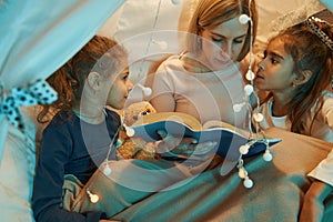 Mother reading book to her girls at home