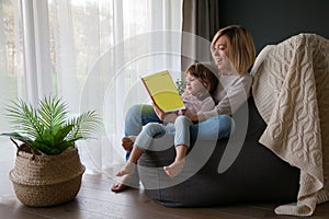 Mother reading book to her little daughter