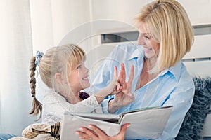 Mother reading a book to her young daughter at home