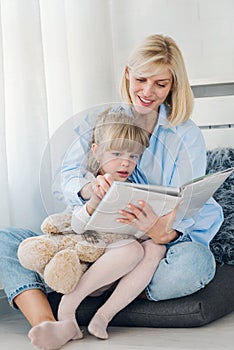 Mother reading a book to her young daughter at home