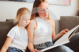 Mother reading book to toddler daughter in bedroom for good night