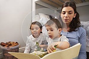 Mother Reading Story To Children In Their Bedroom