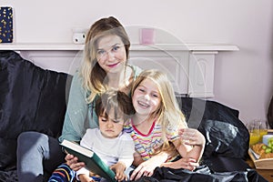 Mother reading to kids in bed