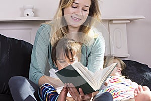 Mother reading to kids in bed