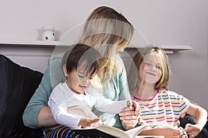 Mother reading to kids in bed