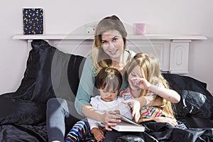 Mother reading to kids in bed