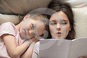 Mother reading to little daughter fairy tale before bed