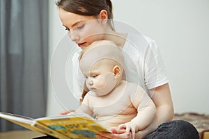 Mother reading to little infant colorful book with fairy tales.