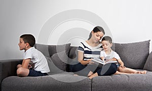 Mother reads an interesting book with her sons. Jealousy concept.