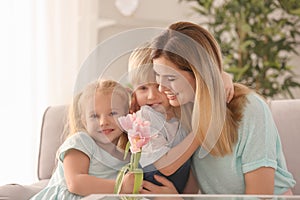 Mother receiving flowers from her cute little children at home