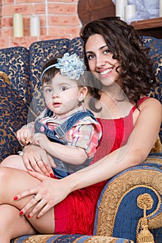 Mother in red dress with little daughter sitting