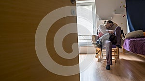 Mother resting on a rocking chair as her child sleeps in her lap