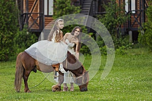 mother rides her daughter on a pony